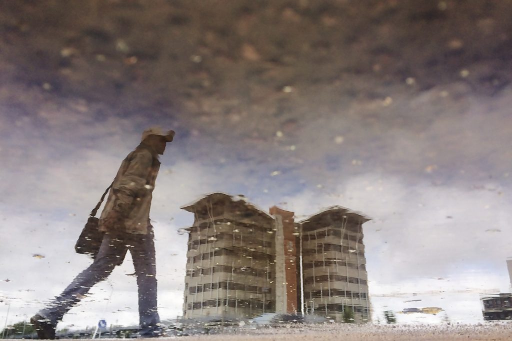 Reflection of man walking on the streets of the CDB shot in a puddle